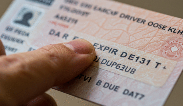 close-up of a hand pointing to the expiration date on an EU driver's license card
